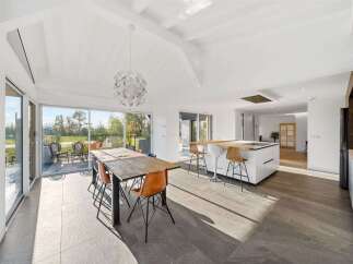 Experience modern living in this spacious open-plan kitchen and dining area, featuring a large island with bar seating and elegant pendant lighting.