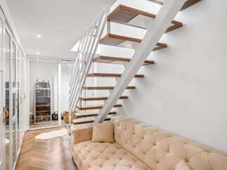 Experience modern living with this stunning staircase featuring floating wooden treads and a sleek white railing.