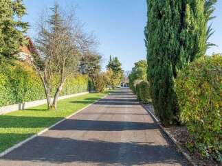 Discover this charming property featuring a long, paved driveway leading to the residence, bordered by lush green lawns and mature trees.
