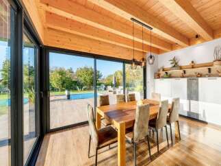 Experience seamless indoor-outdoor living in this stunning dining area, featuring expansive sliding glass doors that open to a sparkling pool and lush garden.