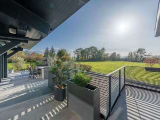Experience modern living with this stunning property featuring a spacious balcony overlooking a lush green landscape.