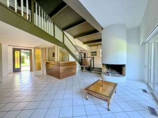 Step into this spacious living area featuring a striking circular fireplace and a built-in wooden bar, perfect for entertaining.