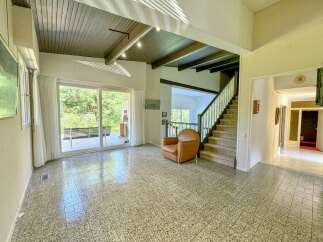 Step into this spacious living area featuring a vaulted ceiling with exposed beams and abundant natural light pouring in through large sliding glass doors.