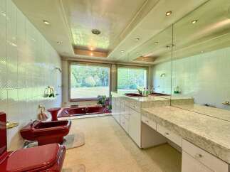 Experience luxury in this unique bathroom featuring a striking red bidet and toilet set against pristine white tiled walls.