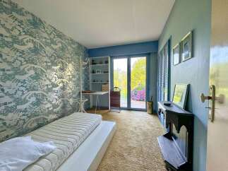 Discover this charming bedroom featuring a unique patterned wallpaper and a comfortable bed.