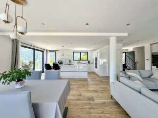 Experience modern living in this spacious open-plan home, featuring a sleek white kitchen with an island and a comfortable living area.