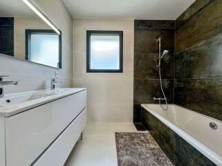 Experience modern luxury in this stunning bathroom featuring a sleek double vanity with chrome fixtures and a large illuminated mirror.