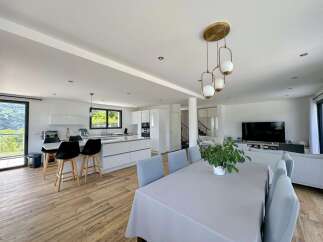 Experience modern living in this open-concept home featuring a sleek white kitchen with a breakfast bar and ample counter space.