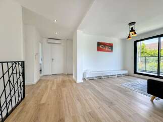 Discover this modern and bright living space featuring a sleek white entertainment unit and a striking piece of art.