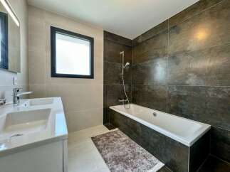 Experience modern luxury in this stunning bathroom featuring a sleek double vanity and a deep soaking bathtub.