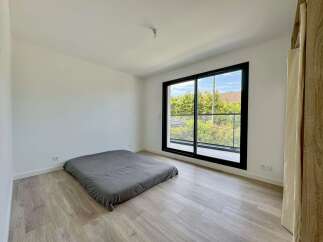 Discover this minimalist bedroom featuring a comfortable grey floor mattress and a large sliding glass door that opens to a private balcony.