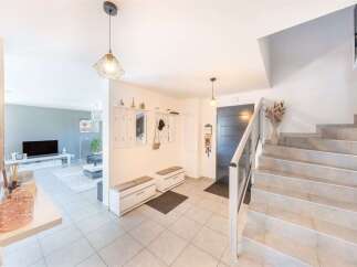 Step into this inviting entryway featuring a modern gray door and a sleek staircase with a glass railing.
