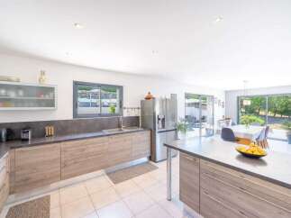 This modern kitchen features sleek, light wood cabinetry and a durable grey countertop, offering ample storage and workspace.