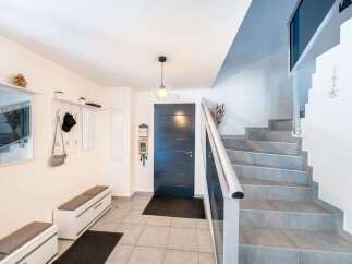 Step into this welcoming entryway featuring a sleek dark gray door and a modern staircase with light gray tiled steps.