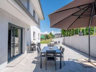 Enjoy outdoor living with this spacious patio featuring a dining set and a large umbrella for shade.