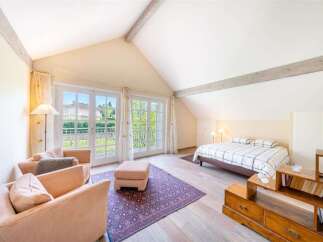 This charming attic bedroom features a vaulted ceiling with exposed wooden beams, creating a cozy and rustic ambiance.