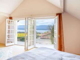 Experience breathtaking lake and mountain views from this charming bedroom, featuring elegant French doors that open onto a private balcony.