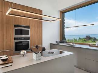 Experience modern luxury in this stunning kitchen featuring sleek, integrated Miele appliances and warm wood cabinetry.