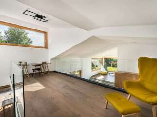 Experience modern living in this stunning loft-style space, featuring a sleek glass railing overlooking a bright, open-concept area with large windows.