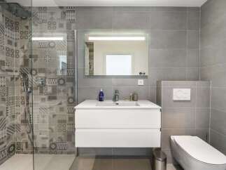 This modern bathroom features a stylish vanity with a white countertop and ample storage, complemented by a large, illuminated mirror.