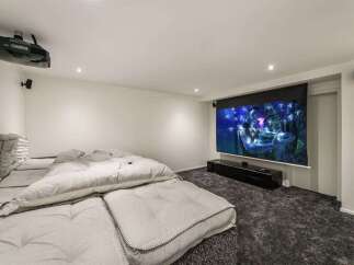 Experience ultimate relaxation in this dedicated home theater room, featuring a large projector screen for an immersive cinematic experience.