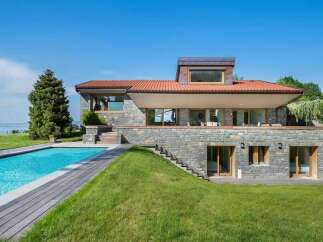 Experience luxury living in this stunning stone-clad home featuring a private swimming pool and expansive green lawns.