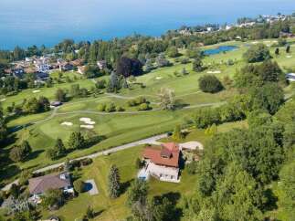 Experience luxury living with this stunning aerial view of a property nestled beside a pristine golf course and overlooking a serene lake.