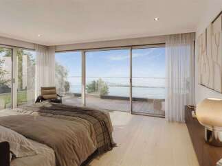Experience luxurious living in this stunning bedroom featuring expansive floor-to-ceiling windows that offer breathtaking panoramic views of the water and surrounding landscape.