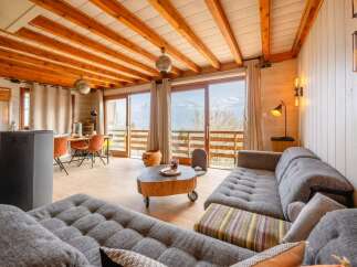 Experience breathtaking mountain views from this stunning living room, featuring a cozy sectional sofa and a unique tree-stump coffee table.