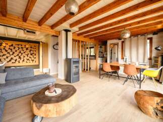 Experience rustic charm and modern comfort in this inviting living space, featuring exposed wooden beams and a cozy pellet stove.