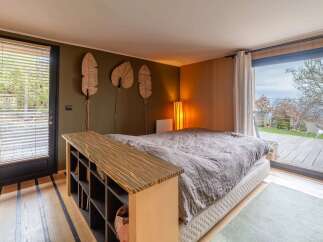 Experience serene living in this master bedroom, featuring a plush king-sized bed and a unique wooden shelving unit.