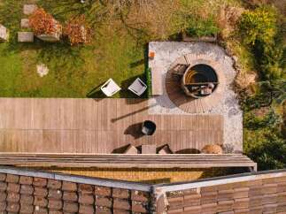 Experience ultimate relaxation in this backyard oasis, featuring a luxurious wooden hot tub surrounded by a serene gravel patio.