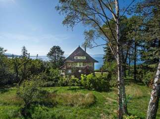 Nestled amidst lush greenery and mature trees, this charming stone house offers a serene retreat with breathtaking lake views.