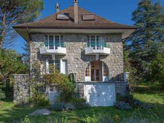 Discover this charming stone house, featuring elegant balconies with green railings and a grand arched entryway.
