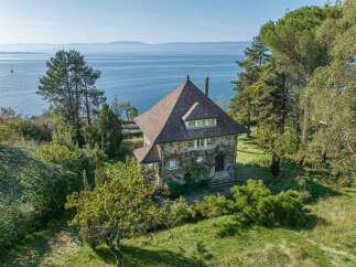 Discover this charming stone house nestled amidst lush greenery, offering breathtaking lake views.