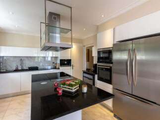 Experience modern luxury in this stunning kitchen, featuring sleek white cabinetry, a marble backsplash, and a spacious black granite island perfect for entertaining.