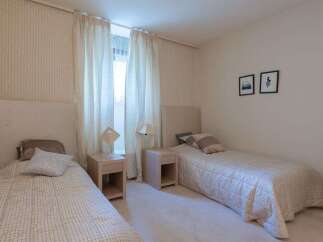This charming bedroom features two twin beds, each with a plush headboard and comfortable bedding.
