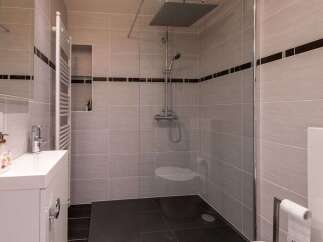 Experience modern comfort in this beautifully appointed bathroom, featuring a spacious walk-in shower with a rainfall showerhead and sleek grey tiling.