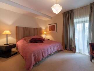 Experience comfort and style in this beautifully appointed bedroom, featuring a plush pink comforter and elegant striped headboard.
