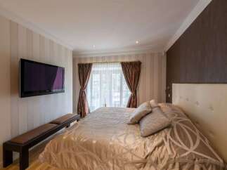 Experience ultimate comfort in this master bedroom, featuring a plush king-size bed with elegant bedding and a stylish tufted headboard.