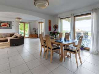 Experience seamless indoor-outdoor living in this spacious dining and living area, featuring a modern sectional sofa and a large dining table perfect for gatherings.
