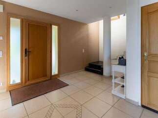 Step into this inviting entryway featuring a warm wooden front door with frosted glass sidelights, leading into a spacious tiled foyer.
