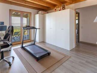 This versatile room offers a perfect blend of home office and fitness space, featuring a modern treadmill positioned on a tasteful rug.