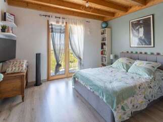 Discover this charming bedroom featuring a comfortable bed with a patterned duvet and a soft grey headboard.