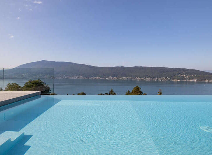 Experience luxury living with this stunning infinity pool offering breathtaking panoramic views of the serene lake and majestic mountains.