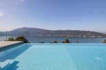Experience luxury living with this stunning infinity pool offering breathtaking panoramic views of the serene lake and majestic mountains.