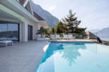 Experience luxury living with this stunning infinity pool overlooking a serene lake and majestic mountains.