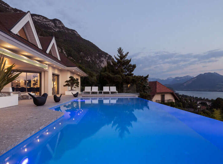Experience luxury living with this stunning infinity pool overlooking a breathtaking mountain and lake view.