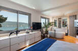 Experience luxury living in this stunning bedroom with breathtaking lake and mountain views through expansive windows.