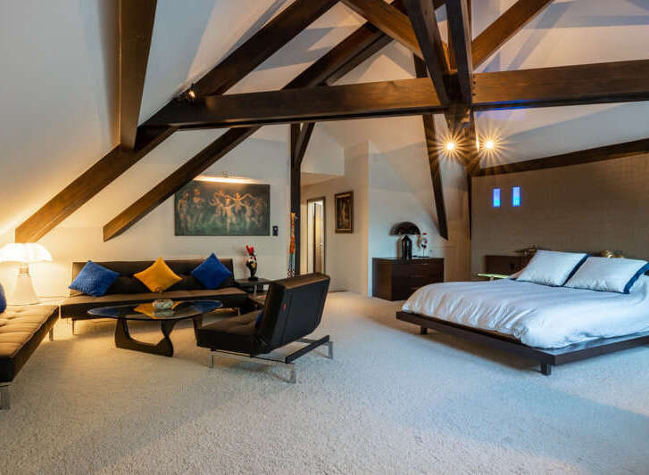Experience luxurious loft living in this stunning bedroom suite, featuring dramatic exposed wooden beams and a vaulted ceiling.